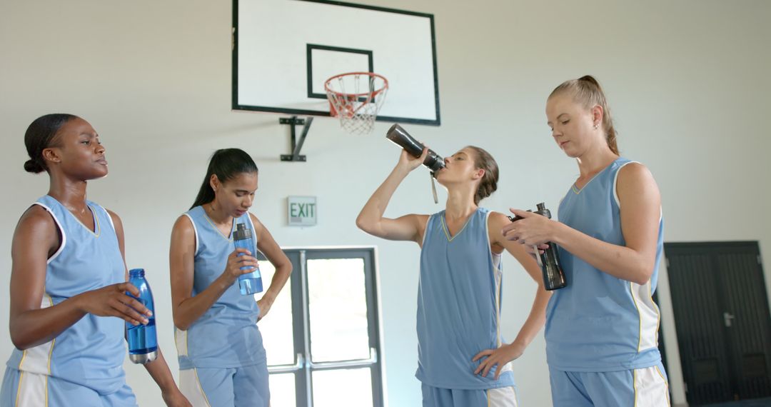 Female Basketball Team Hydrating After Practice in Gym