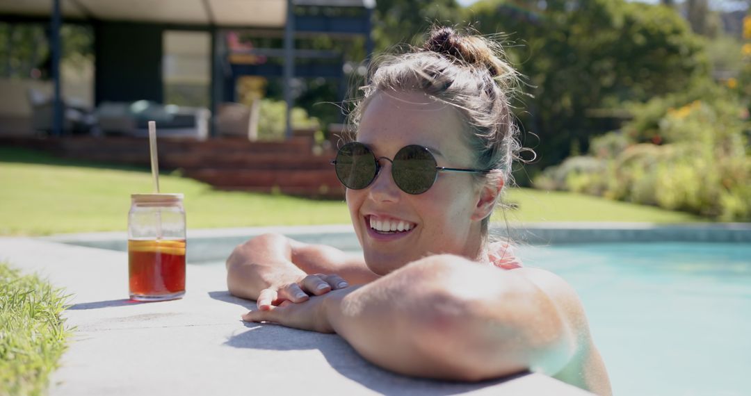 Smiling Woman Relaxing in Pool with Iced Tea on Sunny Day