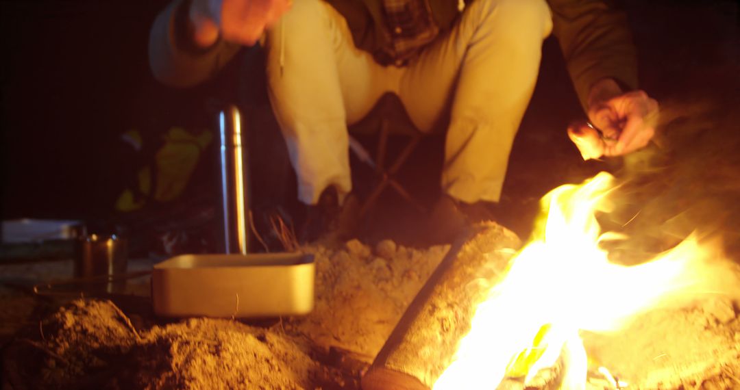 Person enjoying night camping around campfire with cooking equipment - Free Images, Stock Photos and Pictures on Pikwizard.com