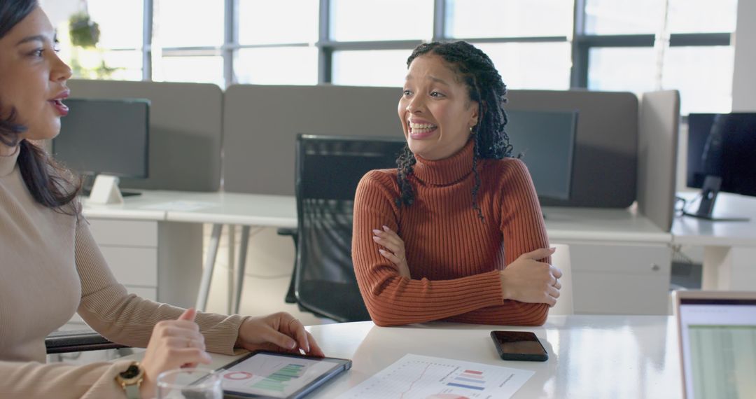 Diverse coworkers collaborating over tablet and charts in modern open-plan office