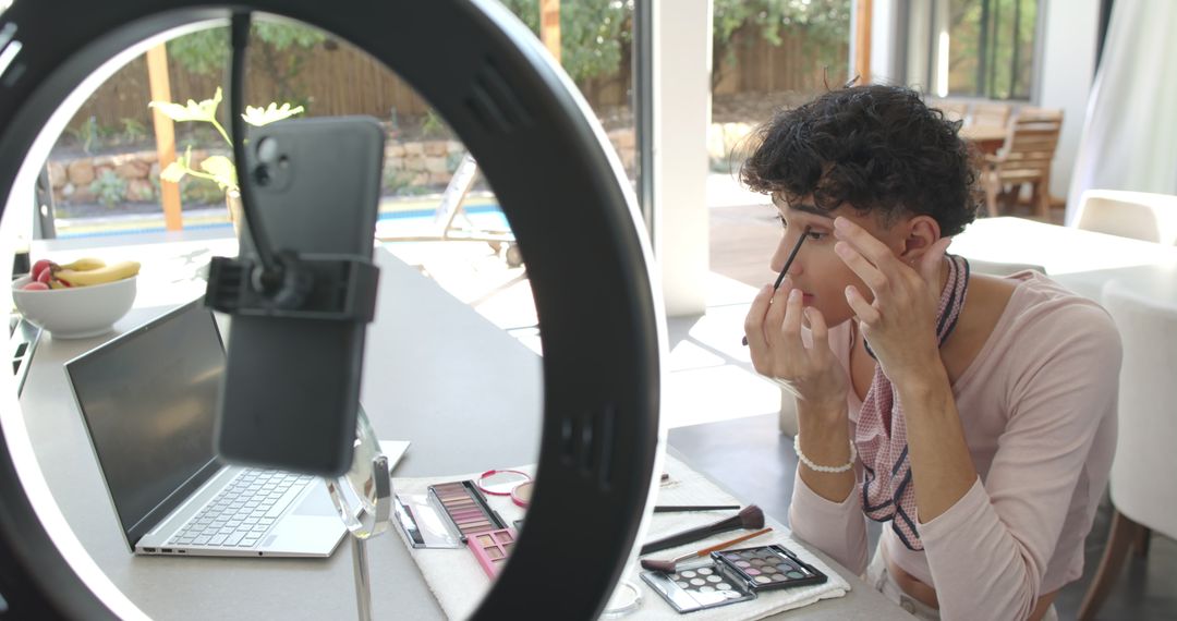Person Applying Makeup Using Smartphone and Ring Light