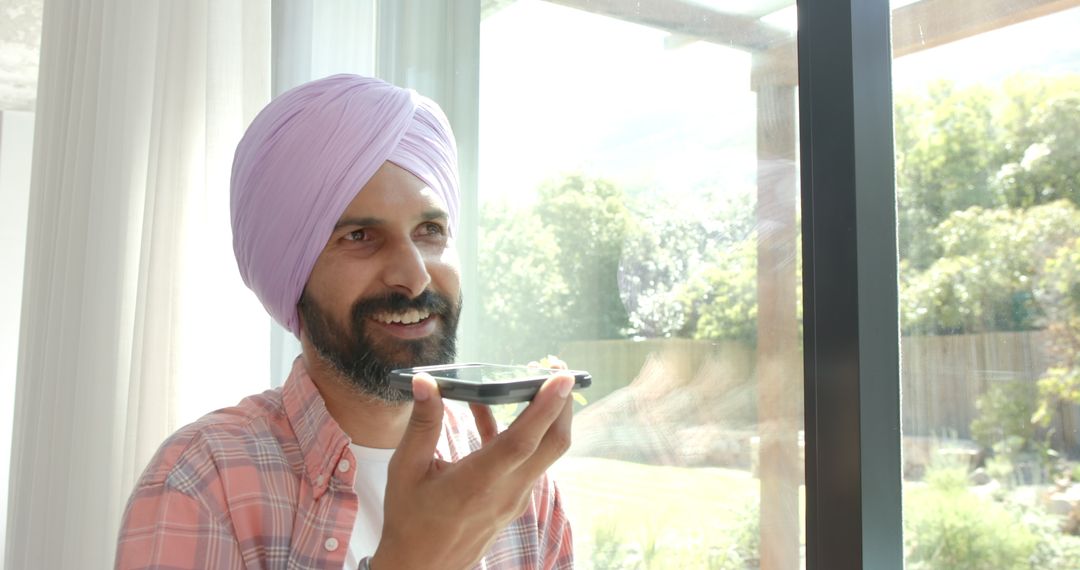 Indian Man with Turban Speaking into Smartphone by Window