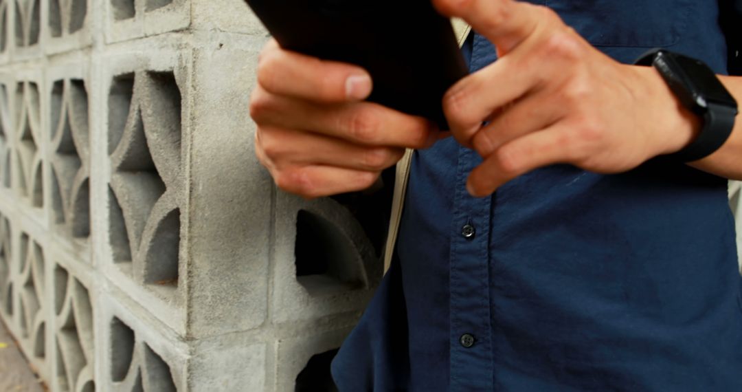 Man using smartphone near decorative concrete wall - Free Images, Stock Photos and Pictures on Pikwizard.com