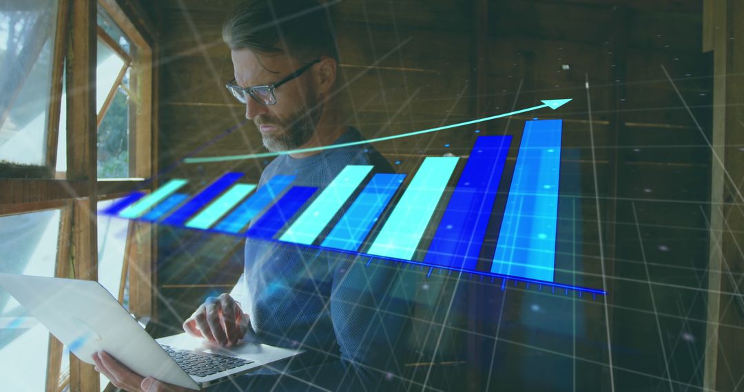 Man Analyzing Data on Laptop with Upward Business Graph Overlay
