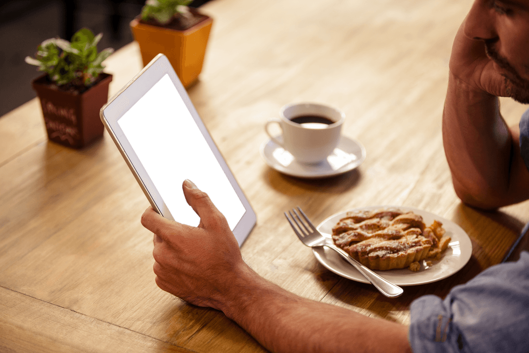 Man Using Tablet in Cafe with Dessert and Coffee on Table