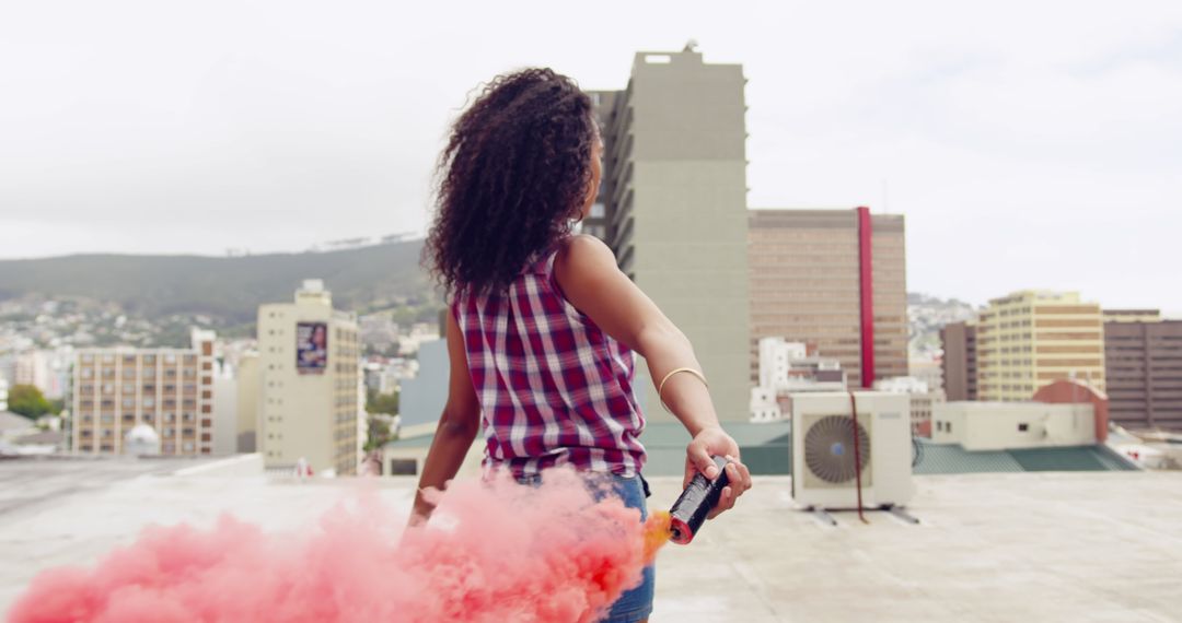 Woman Holding Smoke Bomb on Rooftop with Urban Buildings in Background - Free Images, Stock Photos and Pictures on Pikwizard.com