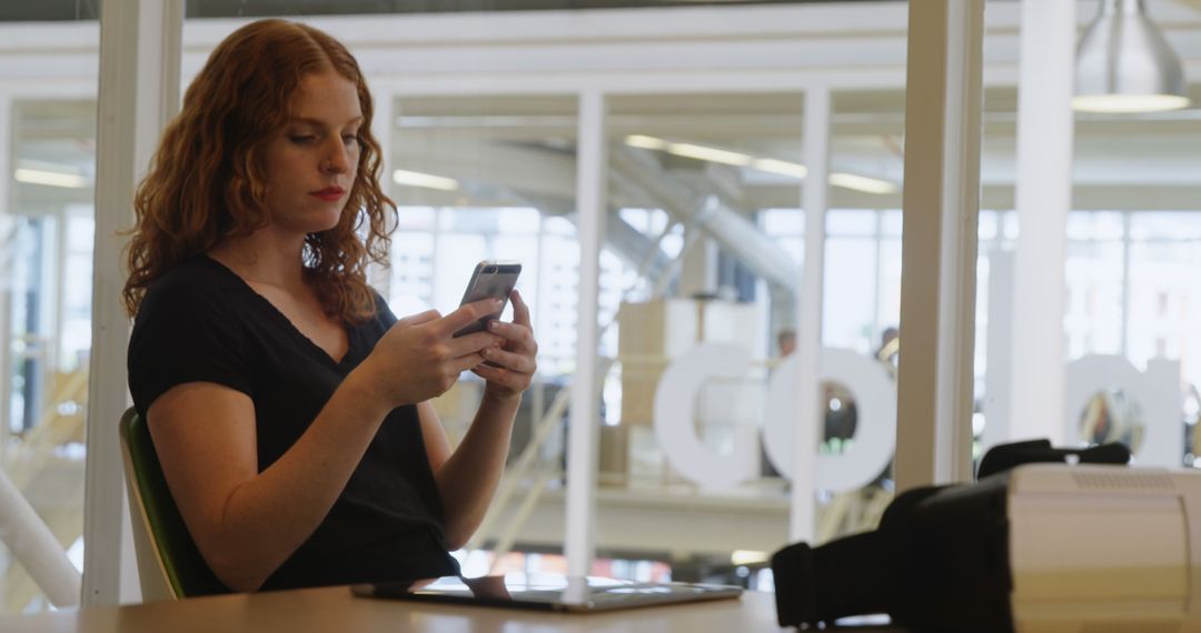 Woman Sitting in Office Typing on Smartphone - Free Images, Stock Photos and Pictures on Pikwizard.com