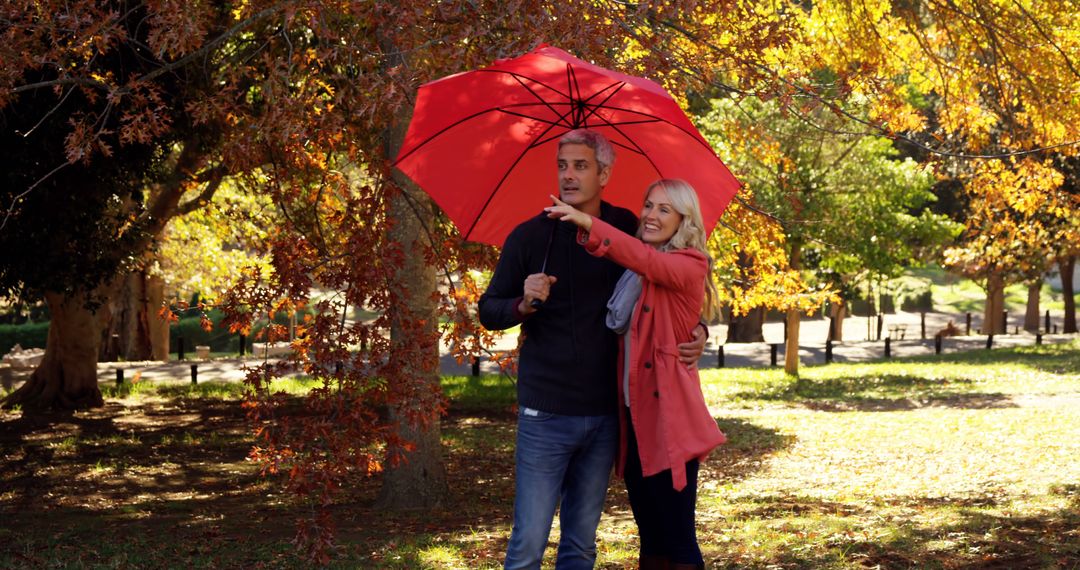 Couple Enjoying Autumn Walk Under Red Umbrella in Park - Free Images, Stock Photos and Pictures on Pikwizard.com