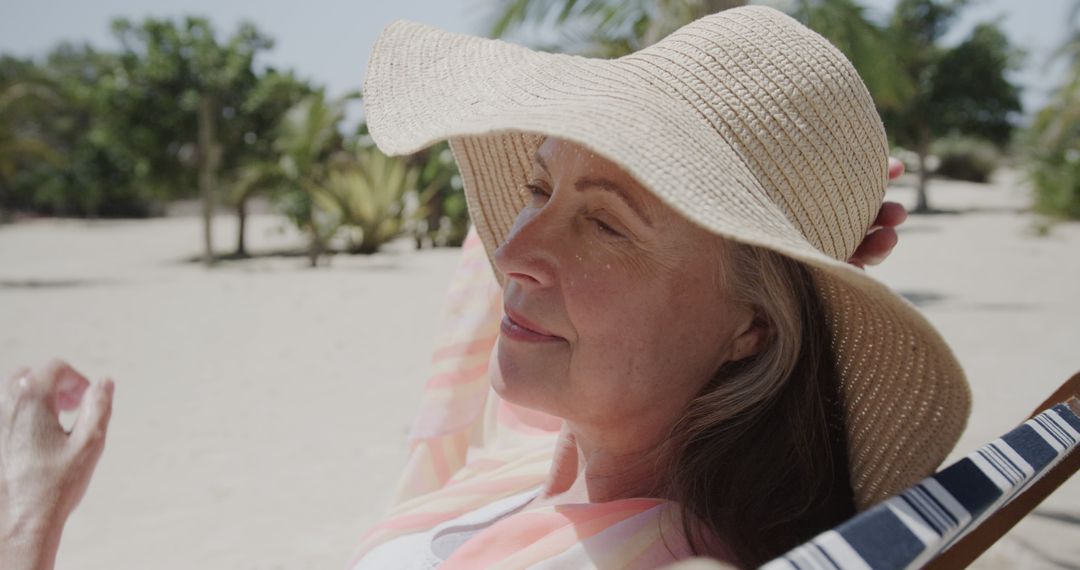 Senior Woman Relaxing on Beach in Wide Brim Hat - Free Images, Stock Photos and Pictures on Pikwizard.com