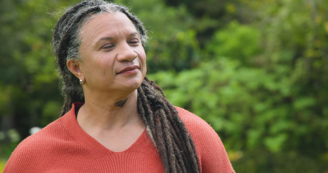 Mature Woman with Dreadlocks Enjoying Tranquility in Lush Garden