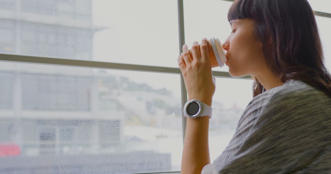 Woman Drinking Coffee by Window in Modern Office Environment