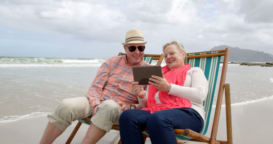 Senior Couple Relaxing on Beach Using Tablet