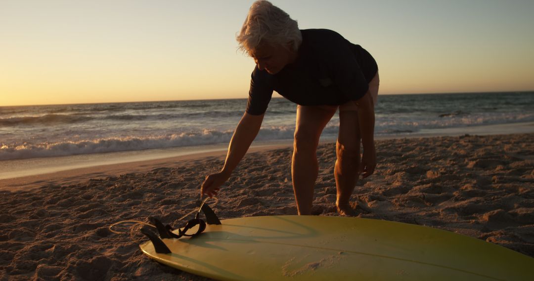 Senior Man Preparing Surfboard at Sunset Beach - Free Images, Stock Photos and Pictures on Pikwizard.com