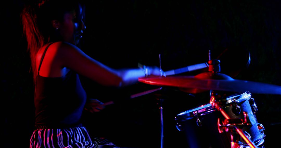 African American woman delivers a vibrant drum performance under moody stage lighting. - Free Images, Stock Photos and Pictures on Pikwizard.com