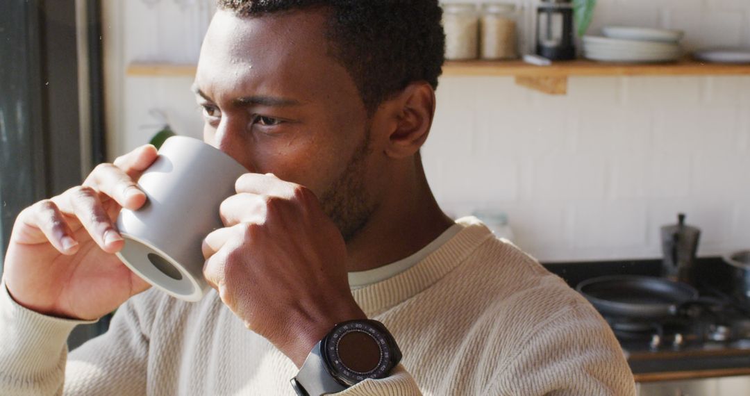 Man Wearing Smartwatch Drinking Coffee in Kitchen Sunlight - Free Images, Stock Photos and Pictures on Pikwizard.com