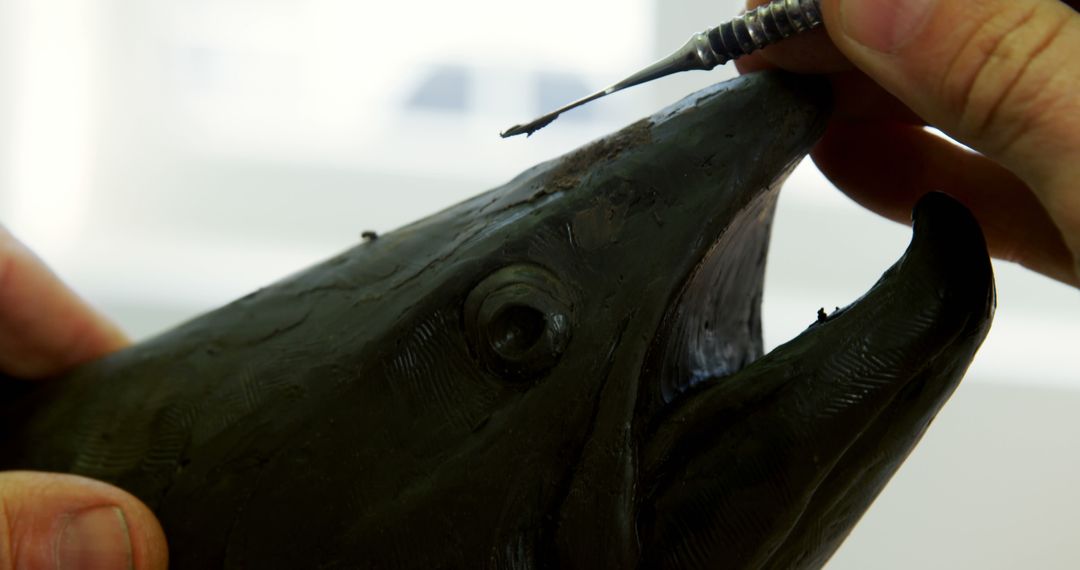 Artisan Restoring Detailed Fish Sculpture with Precision