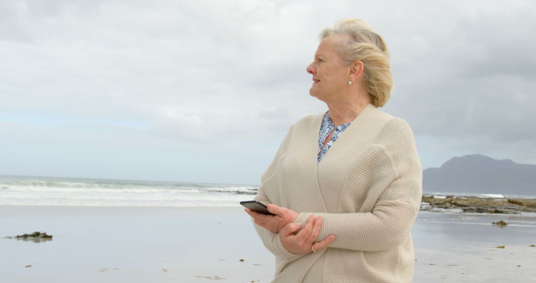 Senior Woman Enjoying Solitude at the Beach While Using Smartphone - Free Images, Stock Photos and Pictures on Pikwizard.com