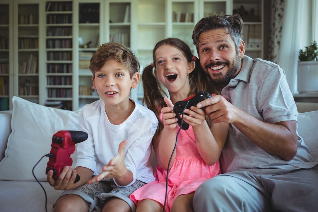 Father sitting on sofa with his children and playing video games - Free Images, Stock Photos and Pictures on Pikwizard.com