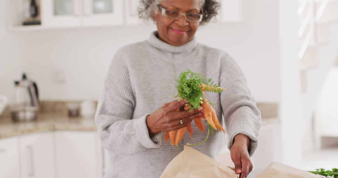 Elderly Woman Preparing Fresh Carrots in Modern Kitchen - Free Images, Stock Photos and Pictures on Pikwizard.com