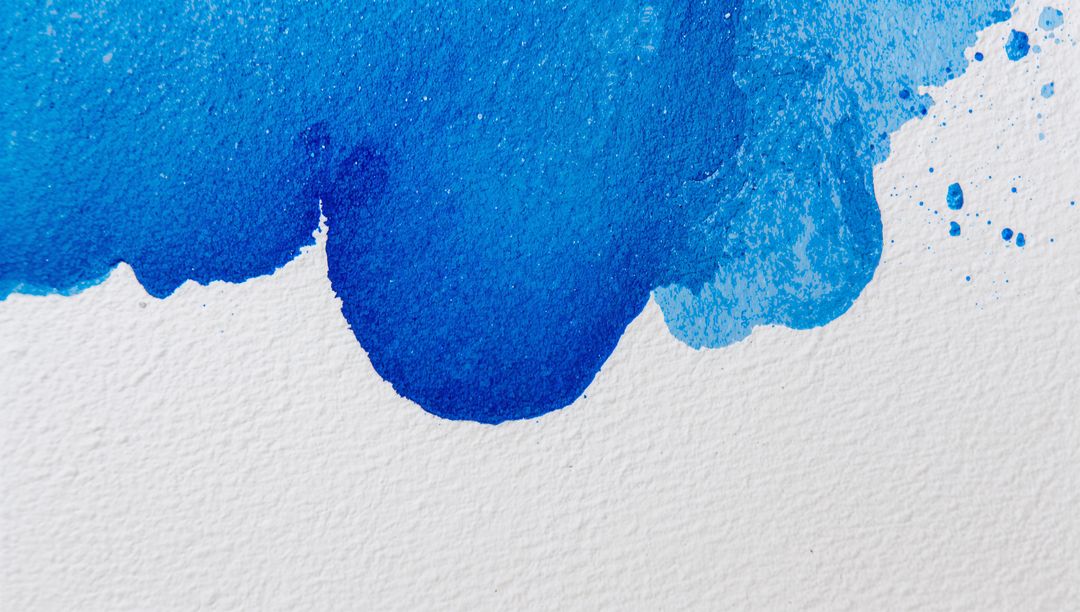 Flowing blue watercolor wash on textured paper showing granulation, drips and splatters