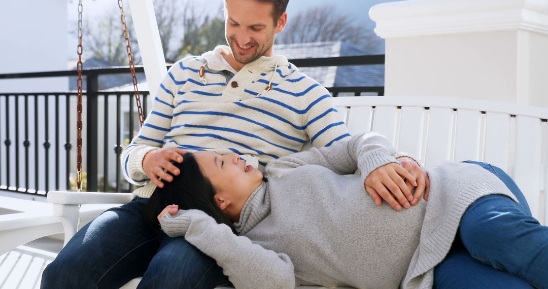 Interracial couple relaxing on porch swing in cozy sweaters - Free Images, Stock Photos and Pictures on Pikwizard.com