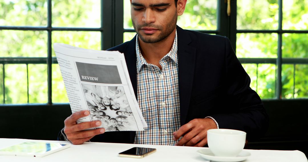 Businessman reading newspaper with coffee at modern cafe - Free Images, Stock Photos and Pictures on Pikwizard.com