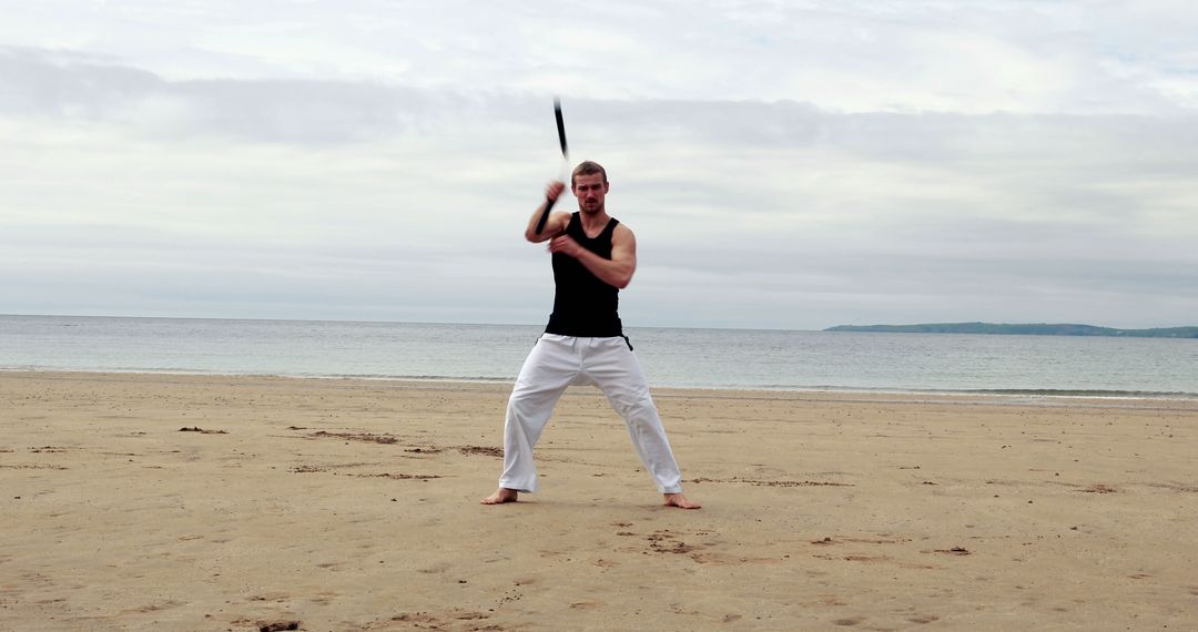 Man Practicing Martial Arts with Weapon on Beach - Free Images, Stock Photos and Pictures on Pikwizard.com