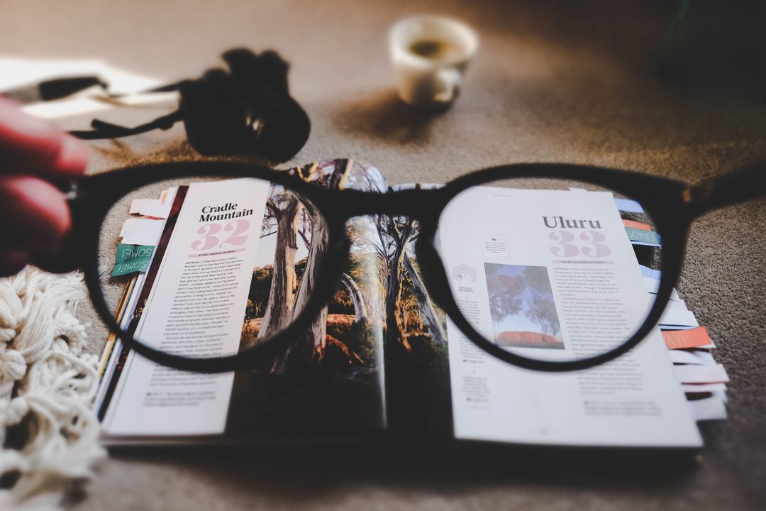 Reading Book through Glasses with Coffee in Background