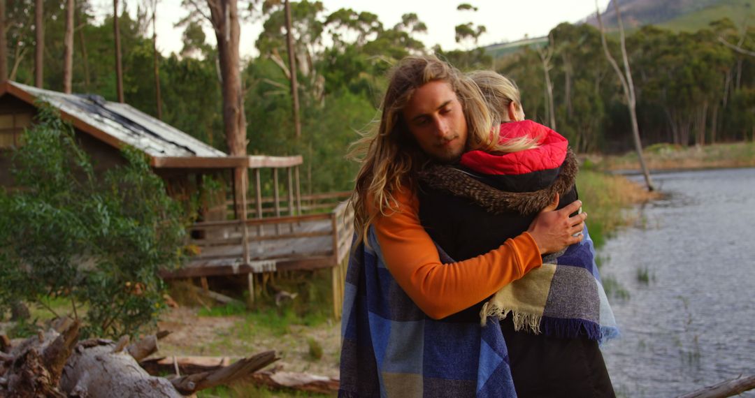 Couple Embracing by Rustic Cabin Near Lake - Free Images, Stock Photos and Pictures on Pikwizard.com