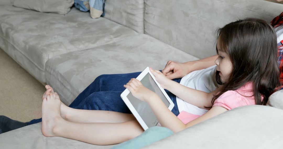 Young Girl Using Tablet Device While Relaxing On Couch - Free Images, Stock Photos and Pictures on Pikwizard.com