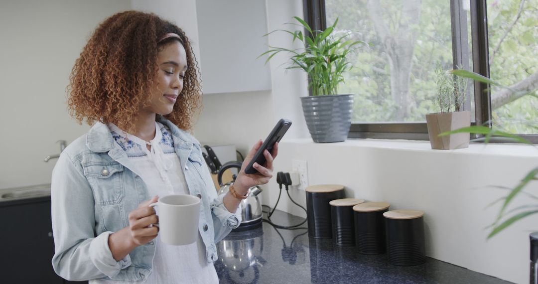 Young Woman Using Smartphone While Drinking Coffee in Modern Kitchen - Free Images, Stock Photos and Pictures on Pikwizard.com