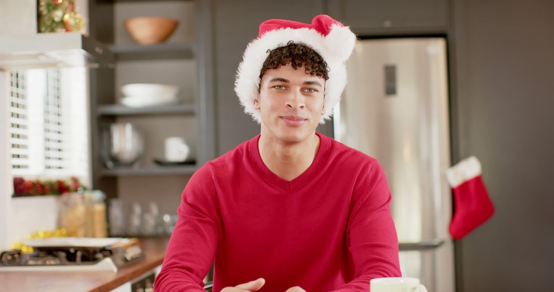 Young Man in Red Sweater and Santa Hat Smiling in Modern Kitchen - Free Images, Stock Photos and Pictures on Pikwizard.com