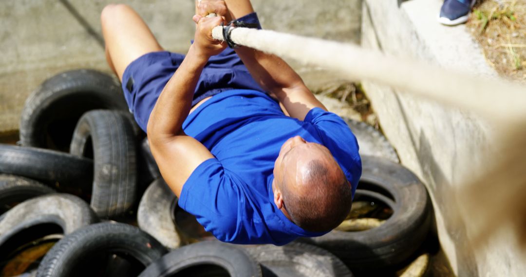 Man Training on Obstacle Course With Tire and Rope Challenge