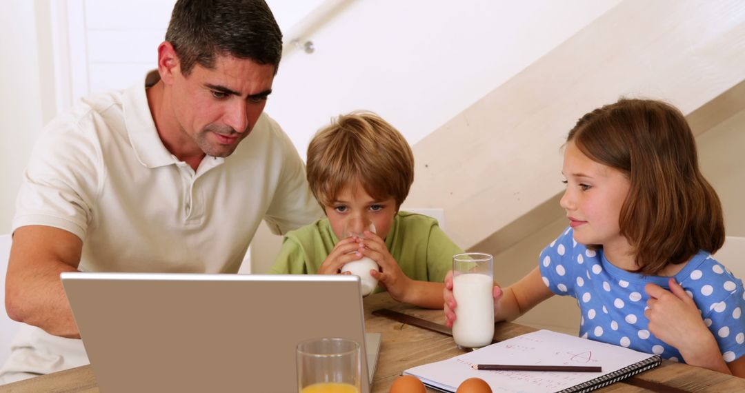 Father Using Laptop While Children Drinking Milk and Doing Homework - Free Images, Stock Photos and Pictures on Pikwizard.com