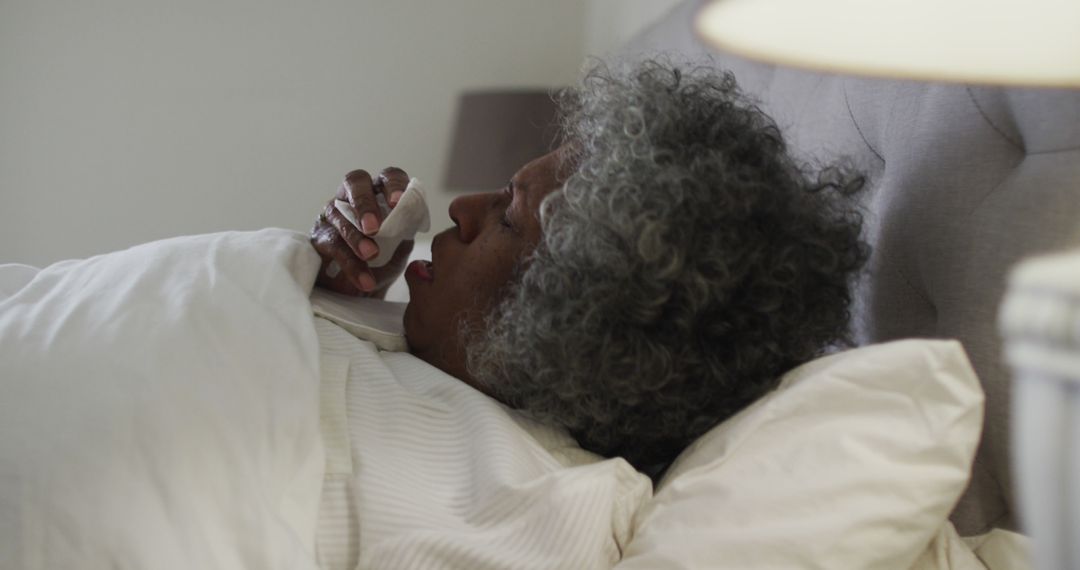 Elderly Woman with Cold Blowing Nose in Bed - Free Images, Stock Photos and Pictures on Pikwizard.com