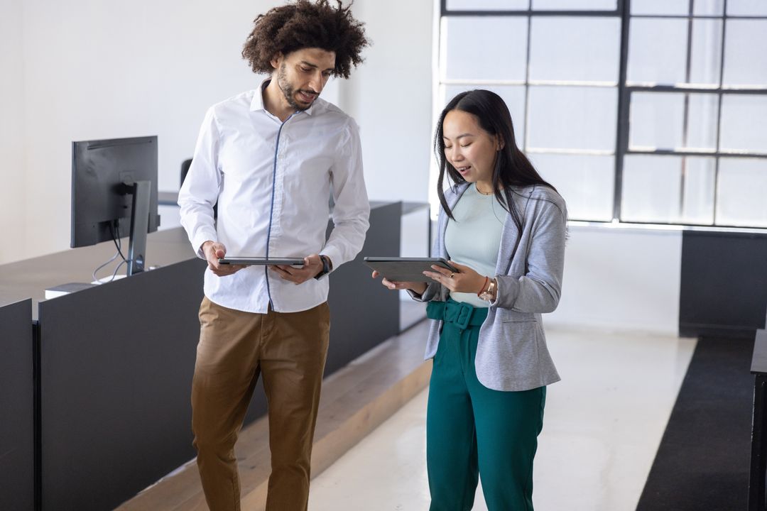 Diverse Coworkers Walking Through Office with Tablets Discussing Data