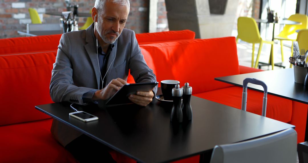 Mature Businessman Using Tablet in Modern Café - Free Images, Stock Photos and Pictures on Pikwizard.com