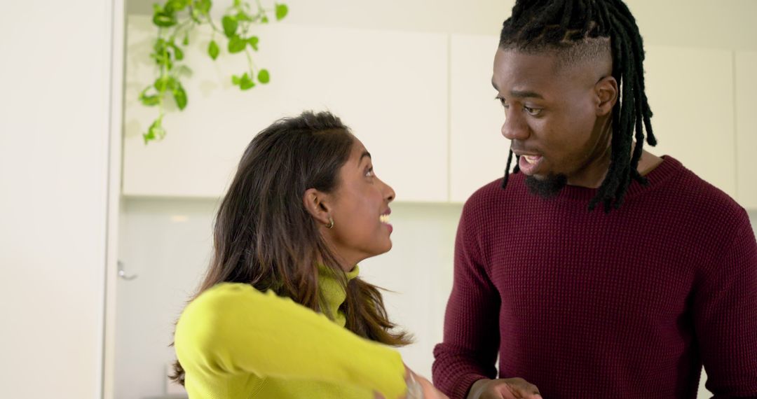 Indian woman and African American man chatting in modern kitchen wearing knit sweaters