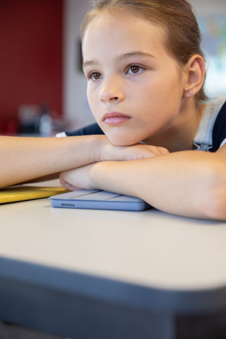Pensive Girl Resting at Desk with Tablet and Notebook