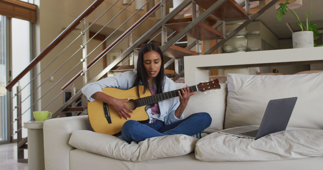 Young Woman Practicing Guitar At Home While Watching Online Tutorial - Free Images, Stock Photos and Pictures on Pikwizard.com