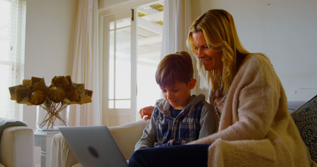 Mother and Son Enjoy Quality Time on Sofa with Laptop