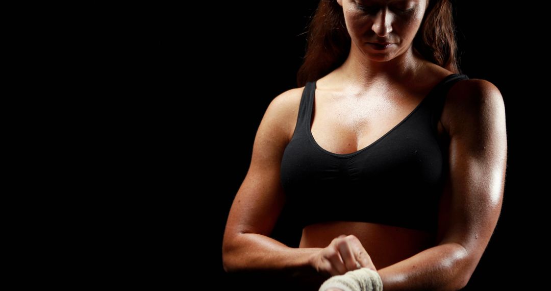 Strong Female Boxer Wrapping Fists in Black Studio