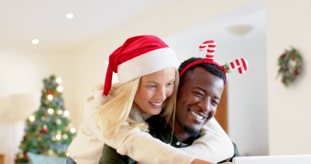 Happy Diverse Couple Embracing Using Laptop Near Christmas Tree