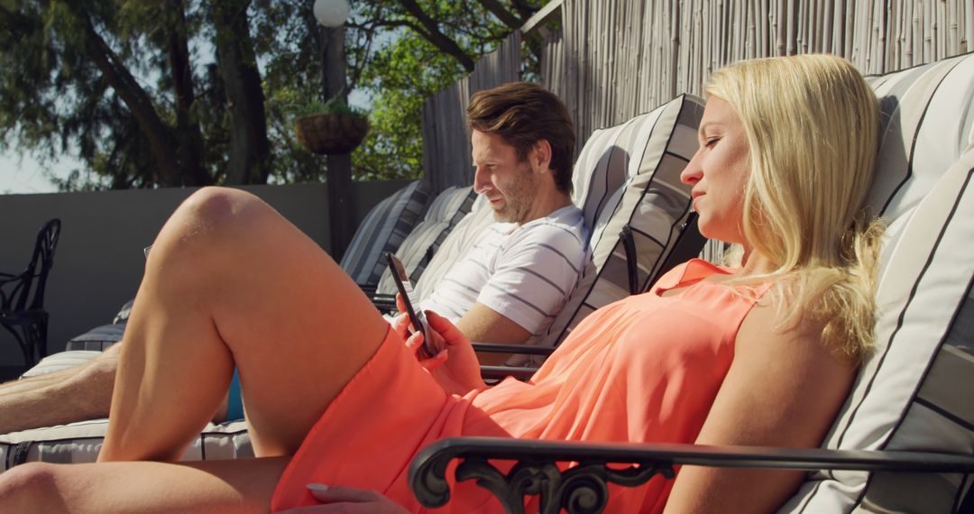 Relaxed Couple Lounging by Pool Enjoying Smartphone