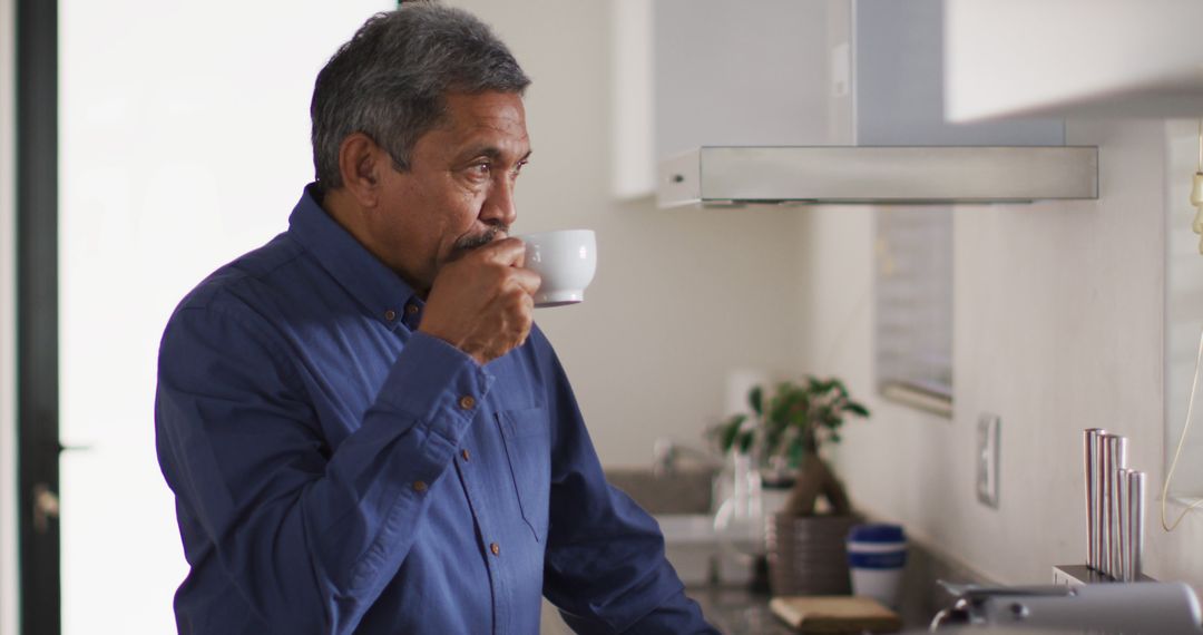 Senior biracial man in kitchen drinking coffee - Free Images, Stock Photos and Pictures on Pikwizard.com