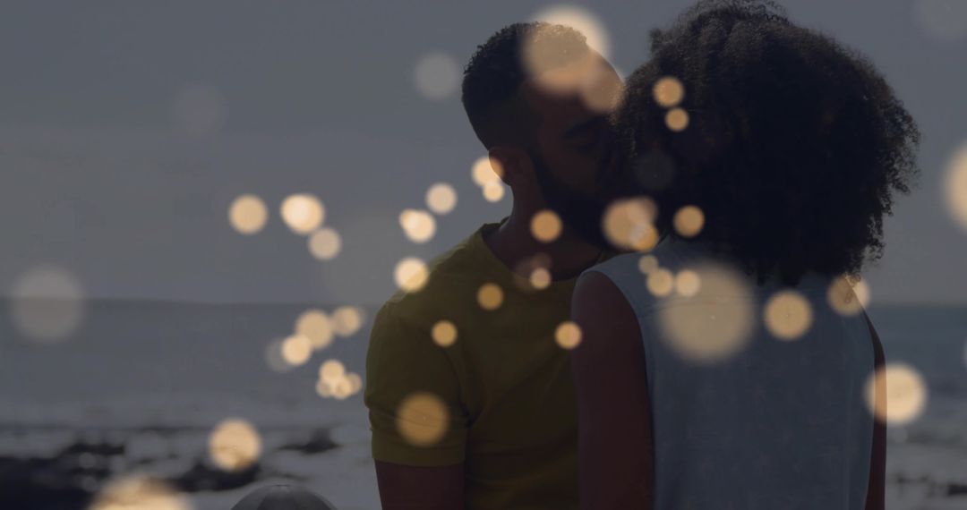 Romantic Couple Kissing by Ocean with Magical Bokeh Lights
