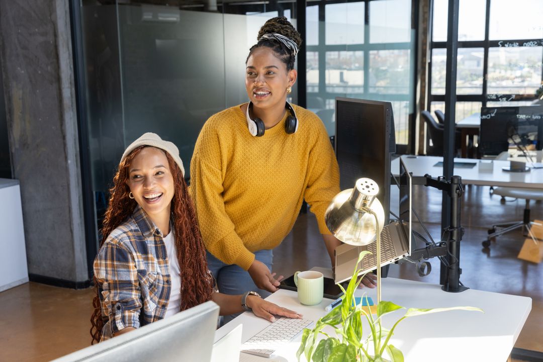 Diverse Women Collaborating in Modern Office, Utilizing Technology