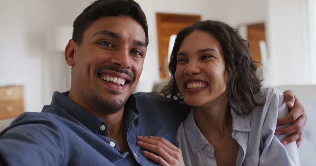 Portrait of happy hispanic couple embracing on sofa in living room - Free Images, Stock Photos and Pictures on Pikwizard.com