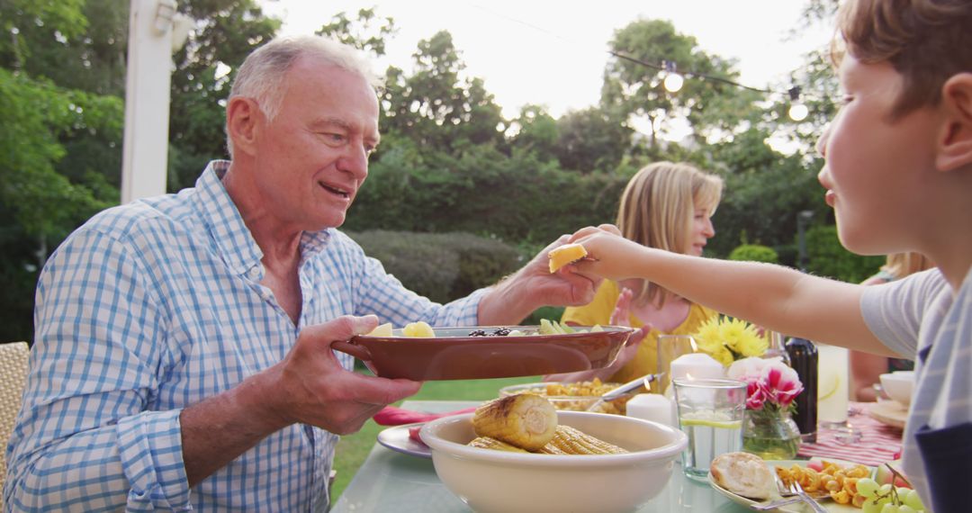 Grandfather Enjoying Outdoor Family Meal at Garden Dining Table - Free Images, Stock Photos and Pictures on Pikwizard.com