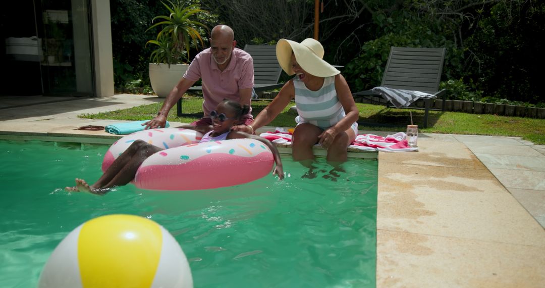Happy Senior Couple Enjoying Summer at Pool with Granddaughter